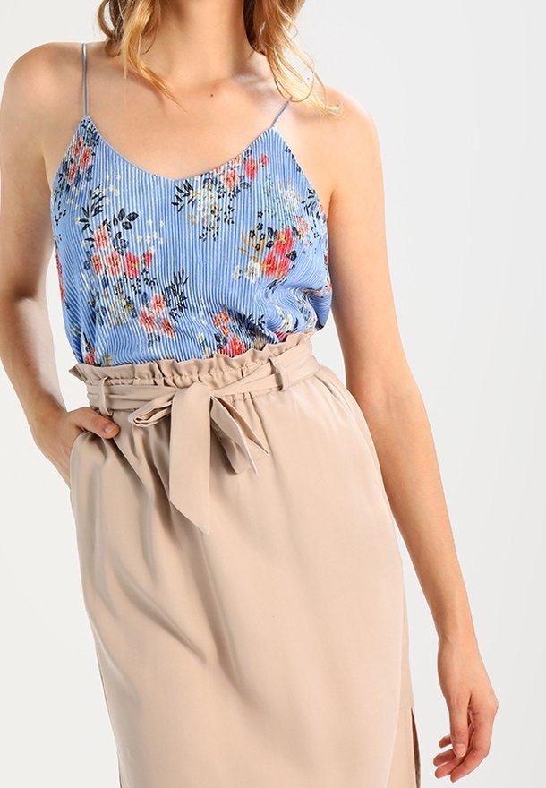 Modrá pruhovaná blůza s květinovým vzorem, doplněná béžovou sukní s vázáním v pase a bočním rozparkem. Hladké textury po celém oblečení.