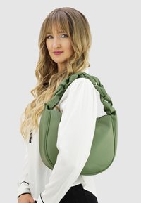 Grüne Lederhandtasche mit strukturierter Oberfläche und geflochtenem Griff, verfügt über eine abgerundete Form und einen Reißverschluss.