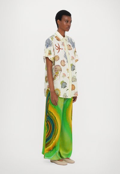 Camicia a maniche corte con bottoni e stampe a tema marino in colori tenui. Pantaloni larghi e fluttuanti verdi con motivi circolari multicolori.