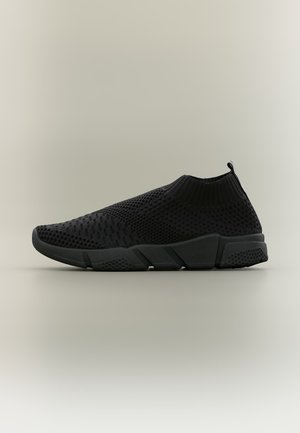 Μαύρο αθλητικό παπούτσι slip-on με πλεκτό διαπνέον πάνω μέρος και υφή στη σόλα, σχεδιασμένο για άνεση και εύκολη χρήση, εμφανίζεται σε ουδέτερο φόντο.
