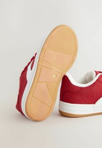 Røde suede sneakers med hvide detaljer og en struktureret gummisål. Har en polstret krave og en kontrastfyldt gummisål.
