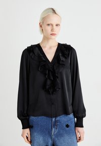 Blusa nera in satin con scollatura a V arricciata, maniche lunghe e chiusura con bottoni. Presenta polsini testurizzati e un tessuto liscio con una finitura lucida.