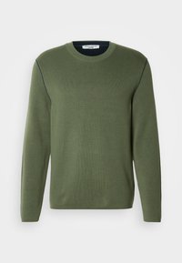 Camisola de malha verde com mangas compridas, decote redondo, textura de malha fina e costuras contrastantes em azul-marinho ao longo dos ombros.