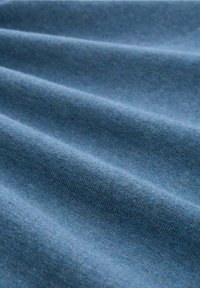 Blauer Stoff mit glatter Textur, der subtile Farbvariationen und mehrere horizontale Falten aufweist. Geeignet für Kleidung oder Polsterung.