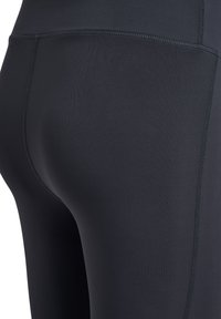 Czarne legginsy sportowe wykonane z elastycznego materiału, z wysokim stanem i gładką teksturą, przeszyte płaskimi szwami dla wygody.