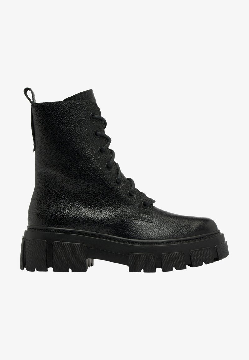 Botín negro de cuero hasta el tobillo con una superficie texturizada, cierre de cordones en la parte frontal y suela gruesa y contundente. Presenta una cinta en la parte trasera para facilitar el calzado.