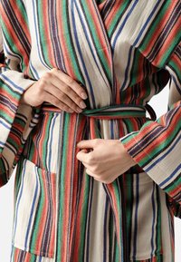 Accappatoio a righe con ampie linee rosse, verdi, blu e nere su uno sfondo crema, dotato di maniche larghe e di una cintura abbinata.