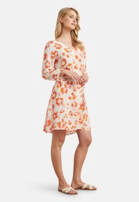 Short-sleeve, knee-length dress made of lightweight fabric with a soft, smooth texture; features an abstract orange and peach leopard print.