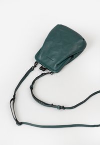 Borsa in pelle verde acqua con una finitura morbida e testurizzata, dotata di una tracolla rimovibile e design minimalista. Include dettagli in hardware neri.