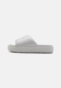 Hvite sandaler med glanset finish, med en bred stropp og teksturert såle for grep. Minimalistisk design, flate, med en bred silhuett.