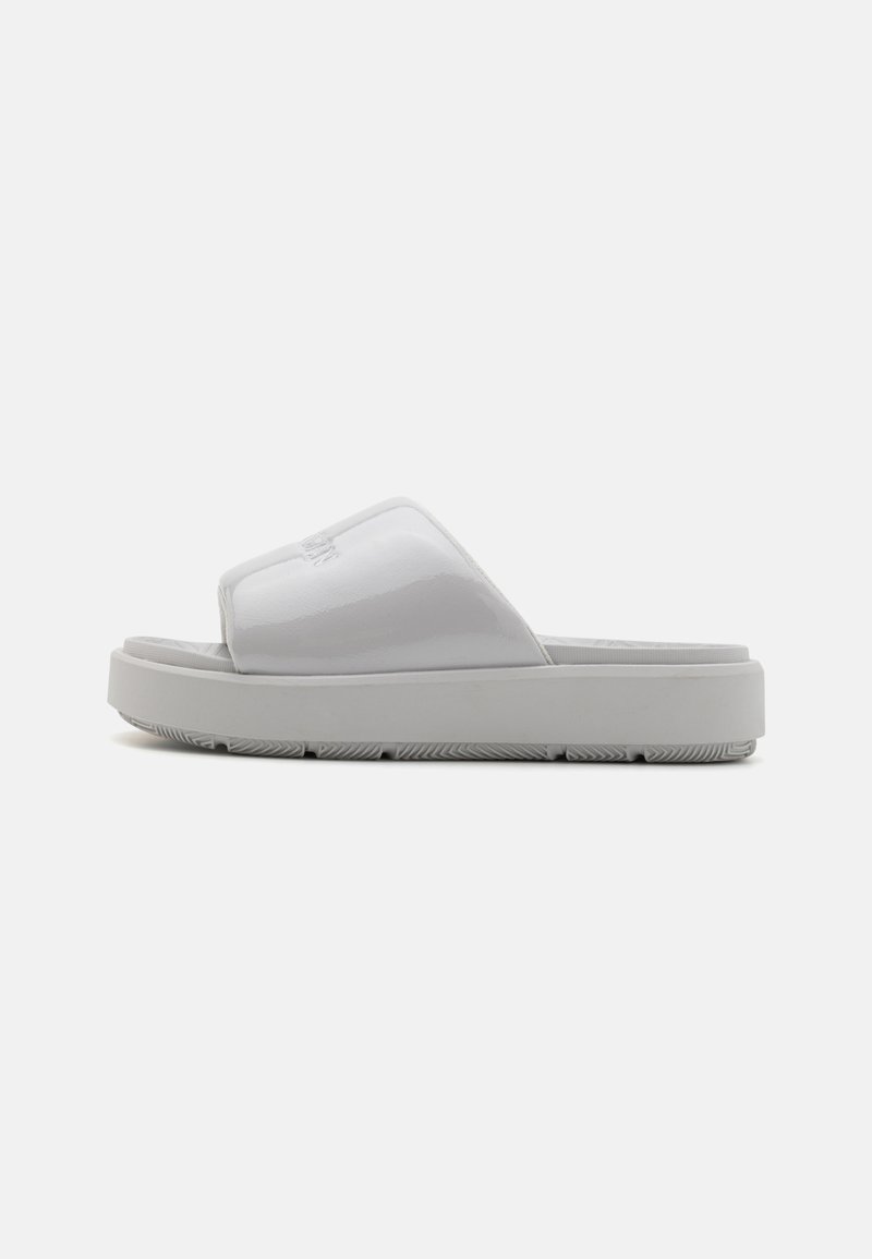 Weiße Rutsch-Sandalen mit glänzender Oberfläche, ausgestattet mit einem breiten Riemen und einer strukturierten Sohle für besseren Halt. Minimalistisches Design, flach und mit einer breiten Silhouette.