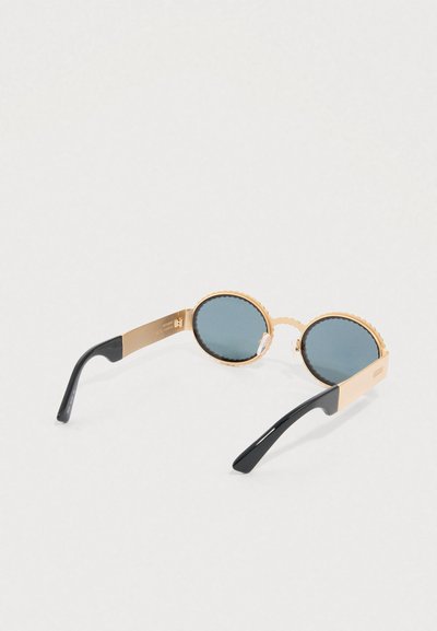 Óculos de sol redondos com armações douradas recortadas e lentes verde-escuro. Apresentam hastes pretas e um detalhe do logótipo na parte lateral.