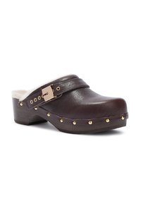 Zoccoli in pelle marrone scuro con borchie dorate, suola spessa, cinturino regolabile con fibbia dorata e rivestimento in pelliccia bianca.