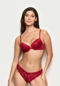 Rød blonder-bh og matchende trusser med underwire-støtte, justerbare stropper og scalloped kanter, der fremviser intrikate blomster mønstre.
