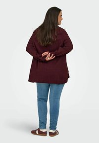 Bordový dlouhý rukáv top, texturovaná tkanina, uvolněný střih, kombinovaný s světle modrými skinny džíny a hnědými teniskami s bílými akcenty.