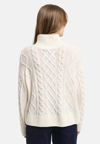 Chunky cream sweater with a high ribbed collar, cable-knit pattern, and long sleeves, featuring textured details on the back.