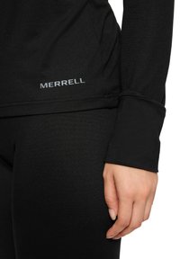 Czarna sportowa bluzka z długim rękawem, o gładkiej fakturze i widocznym szarym logo "MERRELL" na dolnym brzegu. Dopasowany krój.