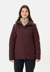 Bordeauxrode waterdichte jas met een getailleerd ontwerp, verstelbare capuchon en een beige binnenlaag. Voorzien van ritsen en logodetail op de borst.