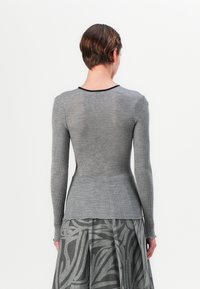 Grå ribbet langermet topp med en tettsittende design, rund hals og svart kant rundt kragen. Bakdelen har en glatt overflate.