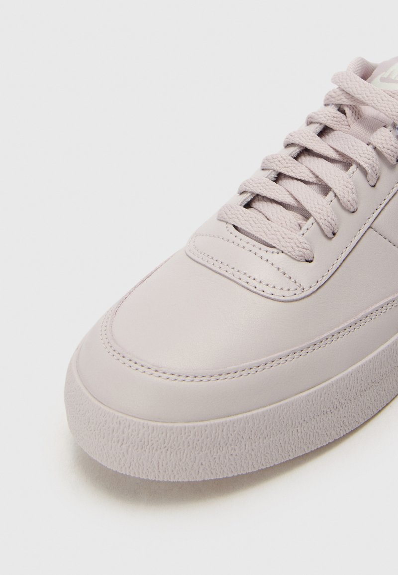Sneaker viola chiaro con tomaia in pelle liscia, punta rotonda e suola in gomma testurizzata. Presenta lacci piatti e dettagli di cucitura sottili.