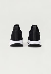 Schwarze Sportschuhe mit einer strukturierten Oberseite, einem schlanken Design und einer weißen Zwischensohle. Verfügt über eine schwarze Fersenlasche und eine Gummisohle.