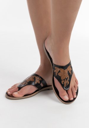 Zwarte leren sandalen met bloemembossing, een v-vormig bandontwerp, open tenen en bruine accenten op een lichte zool.