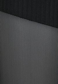 Zwart textiel met een geribbelde bovenste sectie en een fijne mesh onderste sectie, beiden met een subtiel patroon van draden.