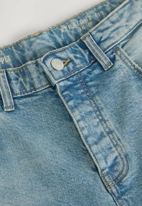 Világoskék, egyenes szabású farmernadrág, fémből készült gombos záródással, topstitching részletekkel és kopott hatású struktúrával, "34 P." felirattal ellátva.