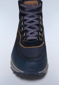 Scarponcino da trekking blu con tomaia testurizzata, occhielli rinforzati e lacci grigi. Presenta una suola imbottita e accenti marroni vicino alla linguetta.
