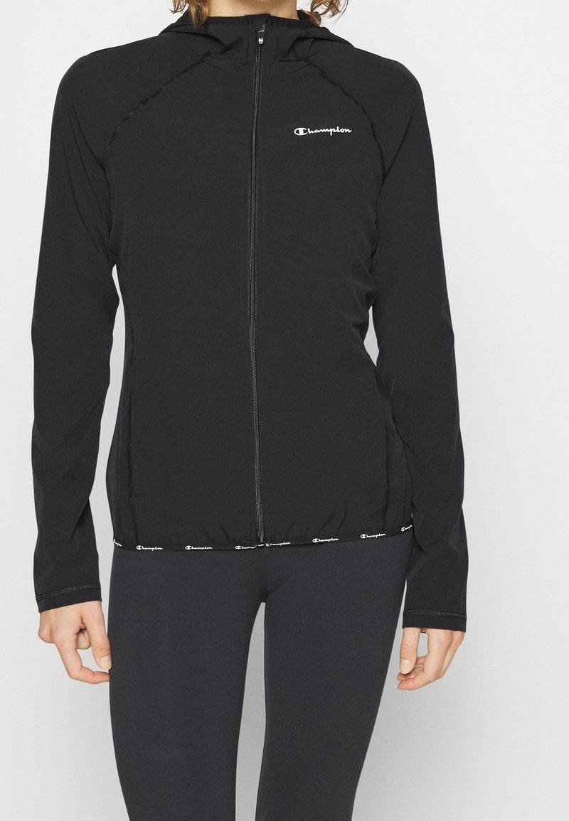 Sort zip-up hoodie lavet af letvægtsstof, med en tætsiddende pasform, hætte og elastisk talje med logo detaljer.