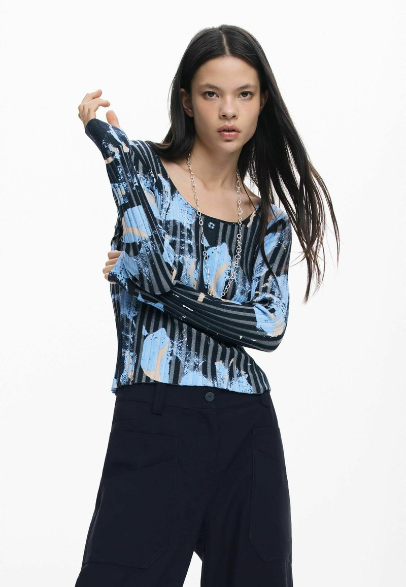 Bluza cu mâneci lungi, albastru-negru, cu modele abstracte, decolteu pătrat și textură nervurată. Purtați peste pantaloni cargo închiși la culoare.