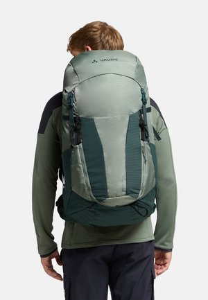 Zaino da trekking verde con un pannello frontale testurizzato, spallacci regolabili e fibbie, che mostra un design slanciato e materiale resistente.