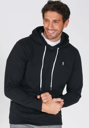 Hoodie noir en coton, avec une poche avant, des cordons blancs et un petit logo sur la poitrine. Coupe confortable et longueur régulière.