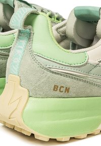 Sneaker verde chiaro realizzate con un mix di materiali scamosciati e in rete. Le caratteristiche includono una suola testurizzata, accenti in verde chiaro a contrasto e il dettaglio 'BCN'.