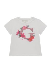 Hvid t-shirt i økologisk bomuld med et glitrende pink bogstav "G" omgivet af blomsterdesign i pink og grøn, med trykknapper på skulderen.