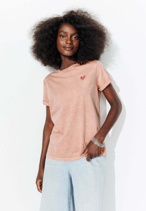 T-shirt en coton rose clair avec des manches roulées ; présente une petite broderie en forme de cœur rouge sur la poitrine. Coupe décontractée, texture douce.
