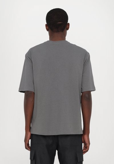 Grå kortærmet t-shirt med løs pasform, lavet af bomuld. Har en ren halsudskæring og lige søm, der viser minimale syninger.