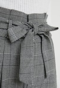 Zwart-wit geruite stof met een gestructureerd oppervlak, voorzien van een strikdetail op de taille en een gestructureerde, op maat gemaakte vorm.