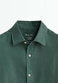 Camicia in lino verde con colletto button-down, placca cucita, bottoni bianchi e etichetta del marchio sulla parte interna del collo.