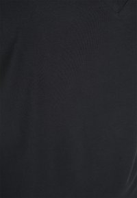 Czarna bawełniana tkanina o gładkiej fakturze, z dekoltem w serek. Powierzchnia ukazuje subtelne wzory cieni, wskazujące na lekki materiał.