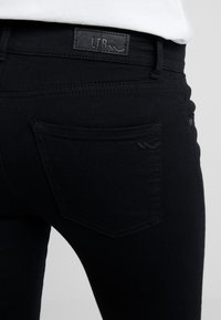 Černé džíny z denimu s koženou nášivkou s nápisem 'LTB'. Design s pěti kapsami, prošitými detaily a hladkou texturou.