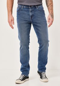 Blaue Denim-Jeans mit einer geraden Schnittführung, ausgestattet mit klassischem Fünf-Taschen-Stil und kontrastierenden Nähten. Getragen mit schwarzen Sneakers.