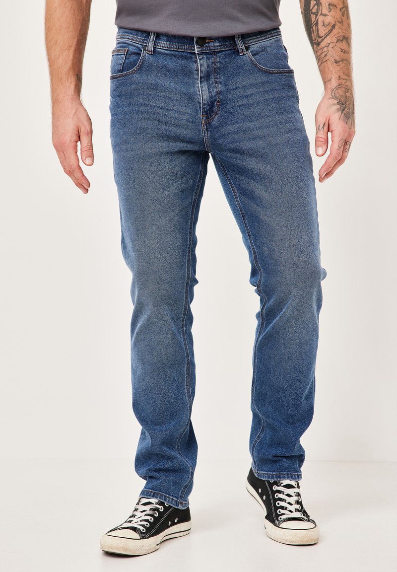Blaue Denim-Jeans mit einer geraden Schnittführung, ausgestattet mit klassischem Fünf-Taschen-Stil und kontrastierenden Nähten. Getragen mit schwarzen Sneakers.