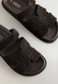 Ciemnobrązowe sandały wsuwane z plecionymi paskami w kwiatowy wzór i miękkimi wkładkami oznaczonymi napisem "NEXT Forever Comfort".