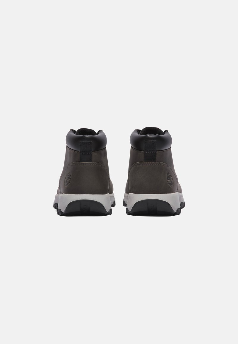 Botas de tobillo de cuero gris oscuro con acentos negros, que cuentan con un cuello acolchado, una solapa y una suela de goma blanca con textura antideslizante.