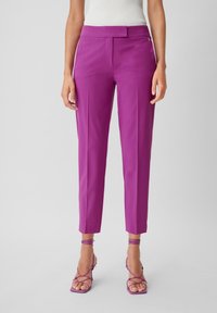 Pantalon violet ajusté avec une texture lisse, jambes fuselées, plis avant et un détail subtil à la taille, associé à des talons à brides assortis.