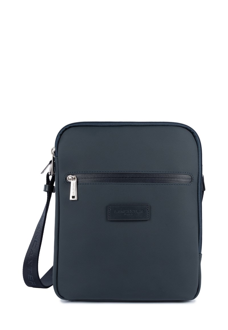 Borsa a tracolla sintetica di colore blu scuro con una tasca frontale con zip, design piatto, dettagli in pelle e tracolla regolabile. Il tirante della zip presenta il marchio.