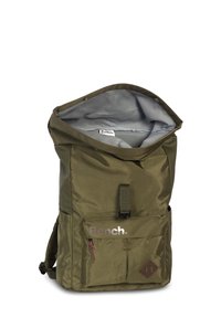 Sac à dos en nylon vert olive avec un rabat supérieur, doublure grise, poche avant et accents marron. Présente un logo à l'avant et des bretelles réglables.