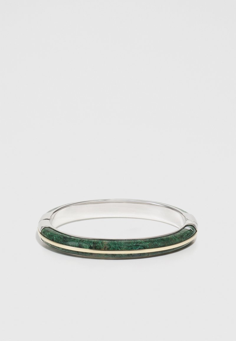 Metalinė apyrankė su žaliu akmeniu, turinti tekstūruotą paviršių, papuošta siauru auksiniu juostelė ir lygiomis sidabrinėmis briaunomis.