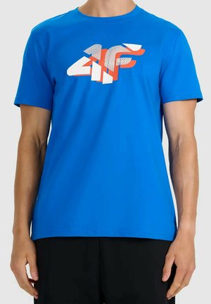 Mężczyzna noszący jasnoniebieską koszulkę z białym i pomarańczowym abstrakcyjnym logo "4F" na piersi, w połączeniu z czarnymi spodniami.